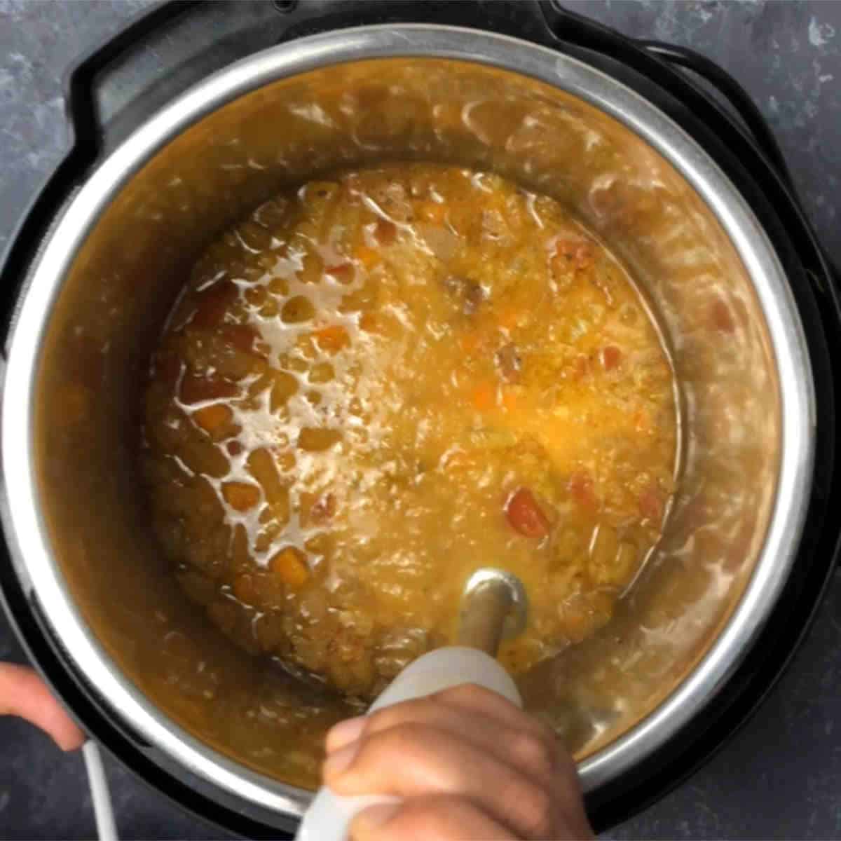 Step showing the blending of soup using an immersion blender.