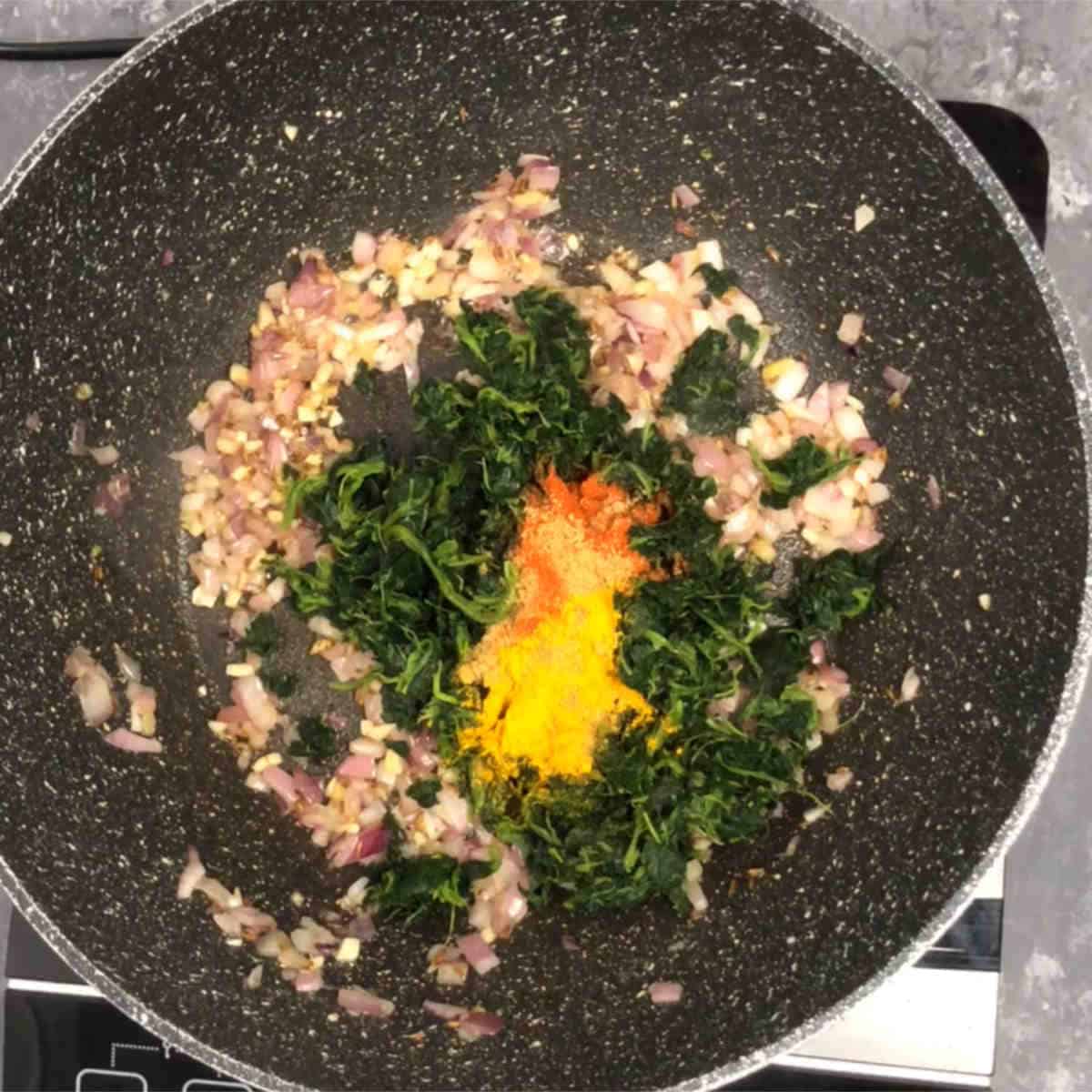 Add spinach and spices to sauteed onions.