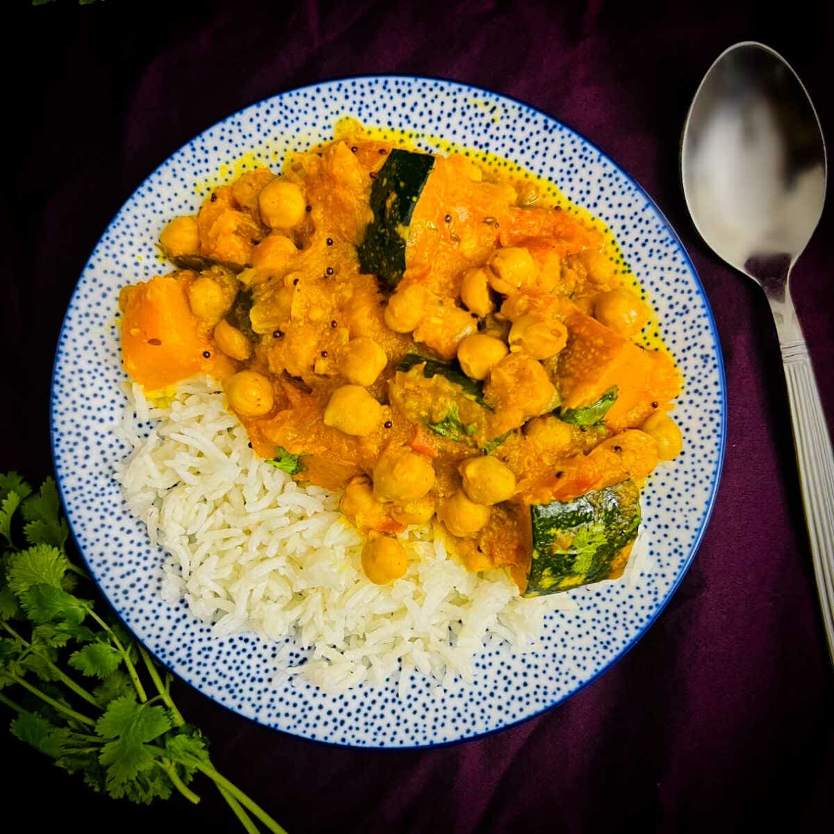Pumpkin chickpea curry and basmati rice served on a plate.