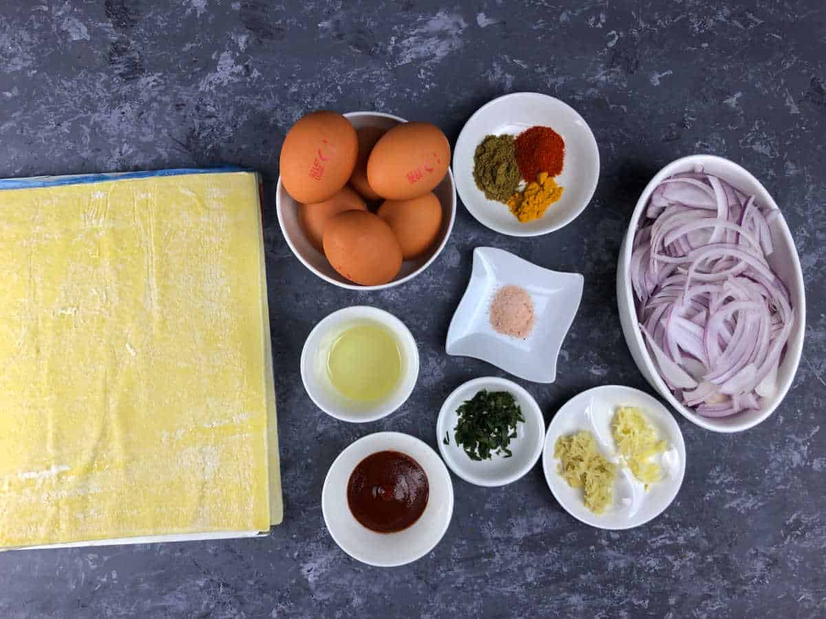 Ingredients to make egg puffs placed on a grey surface.