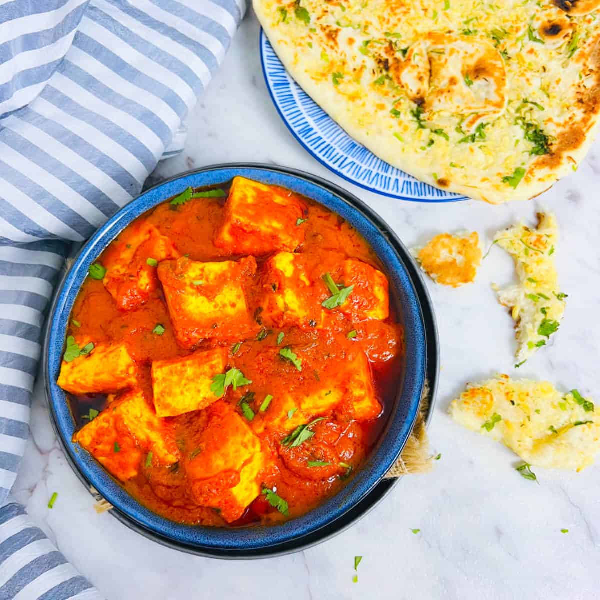 Paneer butter masala placed in a blue bowl.