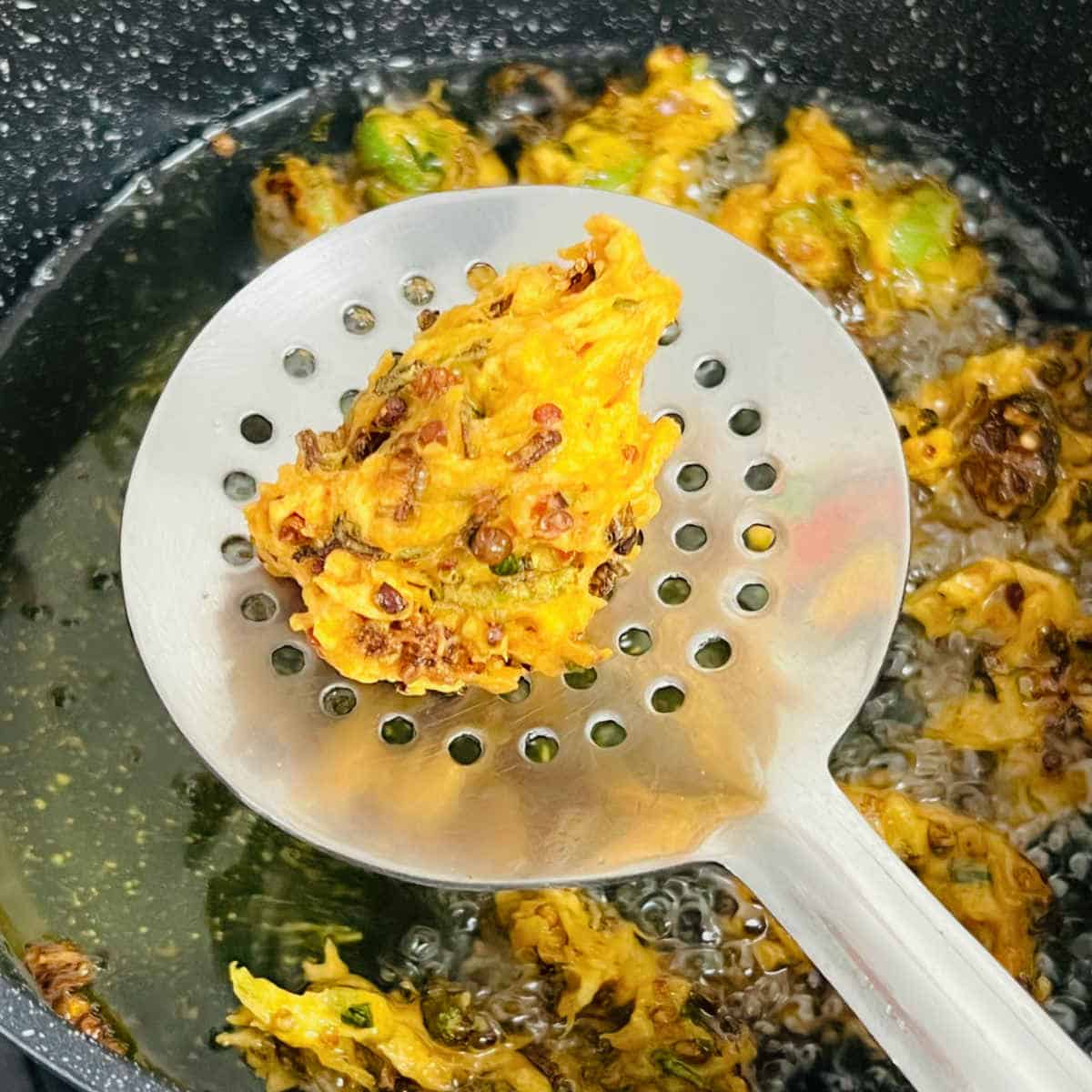 Crispy okra fritters on a slotted spoon.