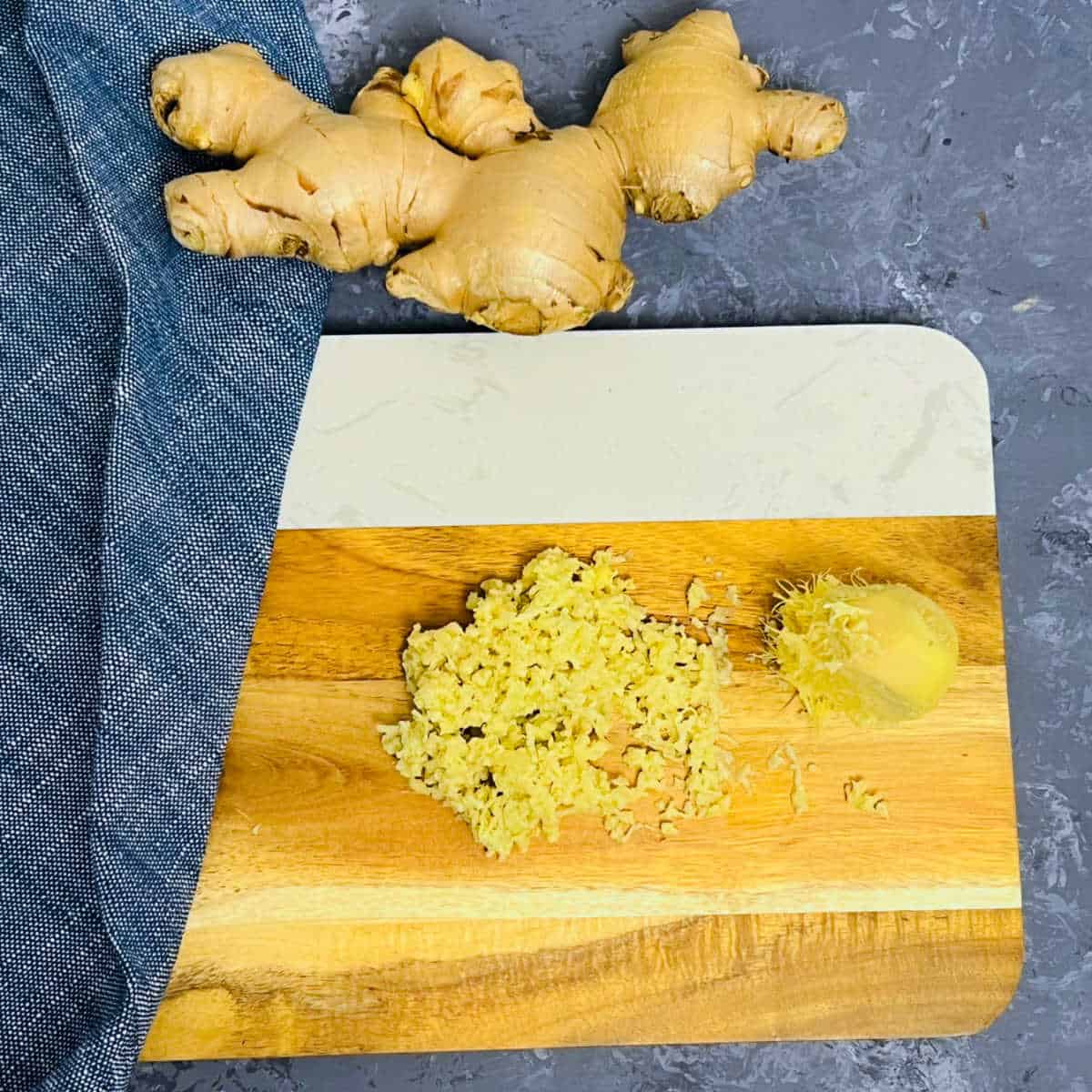 Grated ginger placed on a brown board.
