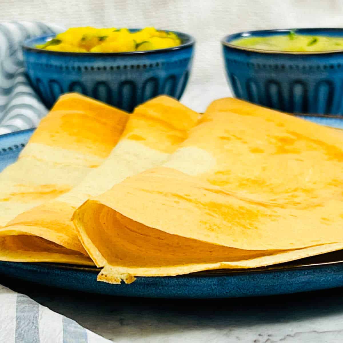 A close up showing the crisiness quinoa dosa that is placed on a blue plate.