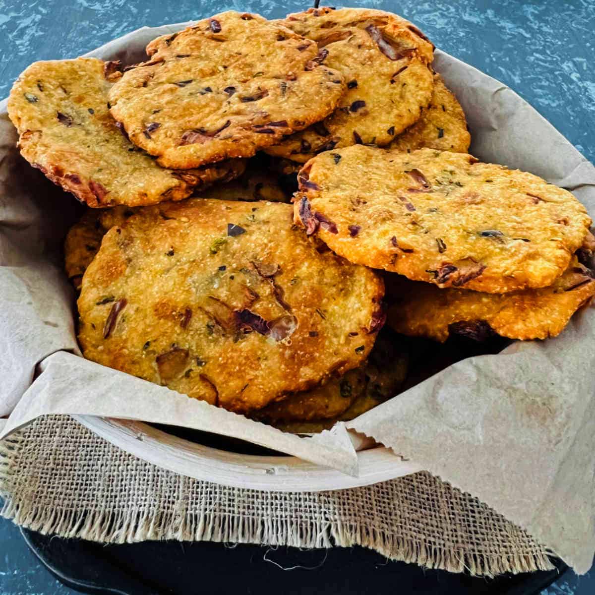Maddur vada placed on a parchment paper inside a jute basket.