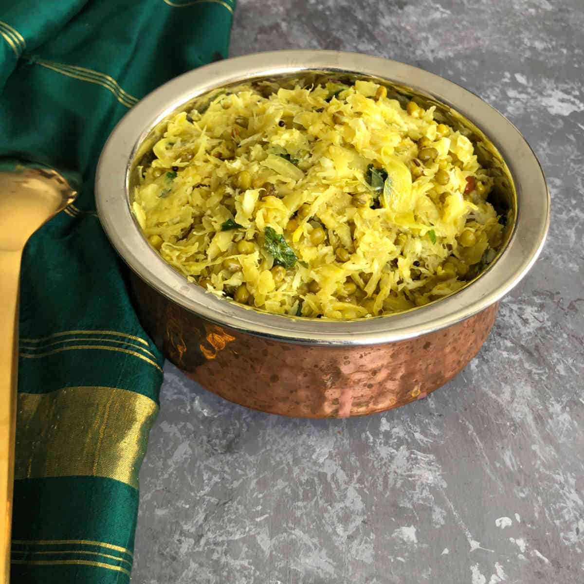 Cabbage poriyal placed in a traditional copper vessel.