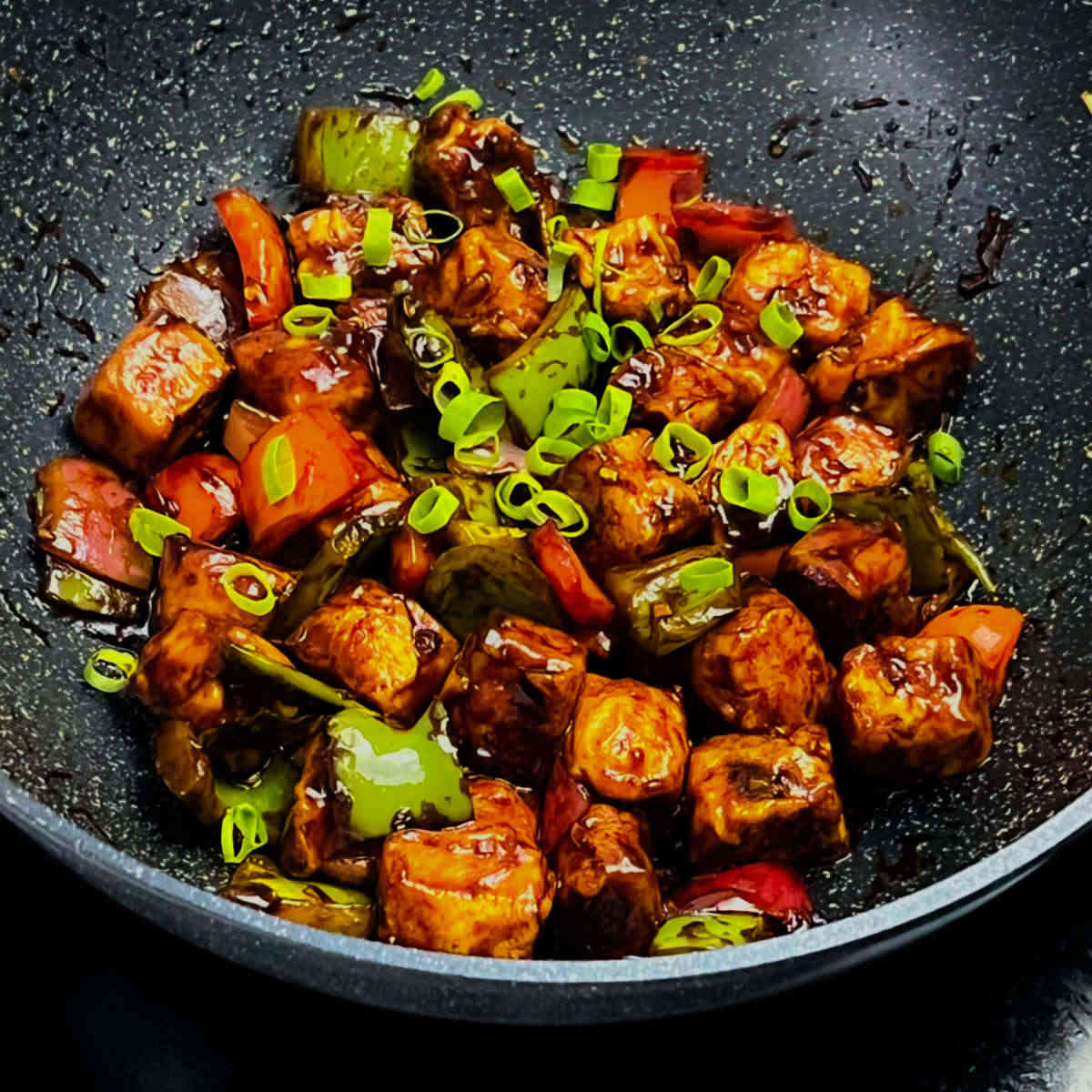 Hot and spicy chilli paneer placed in a frying pan.