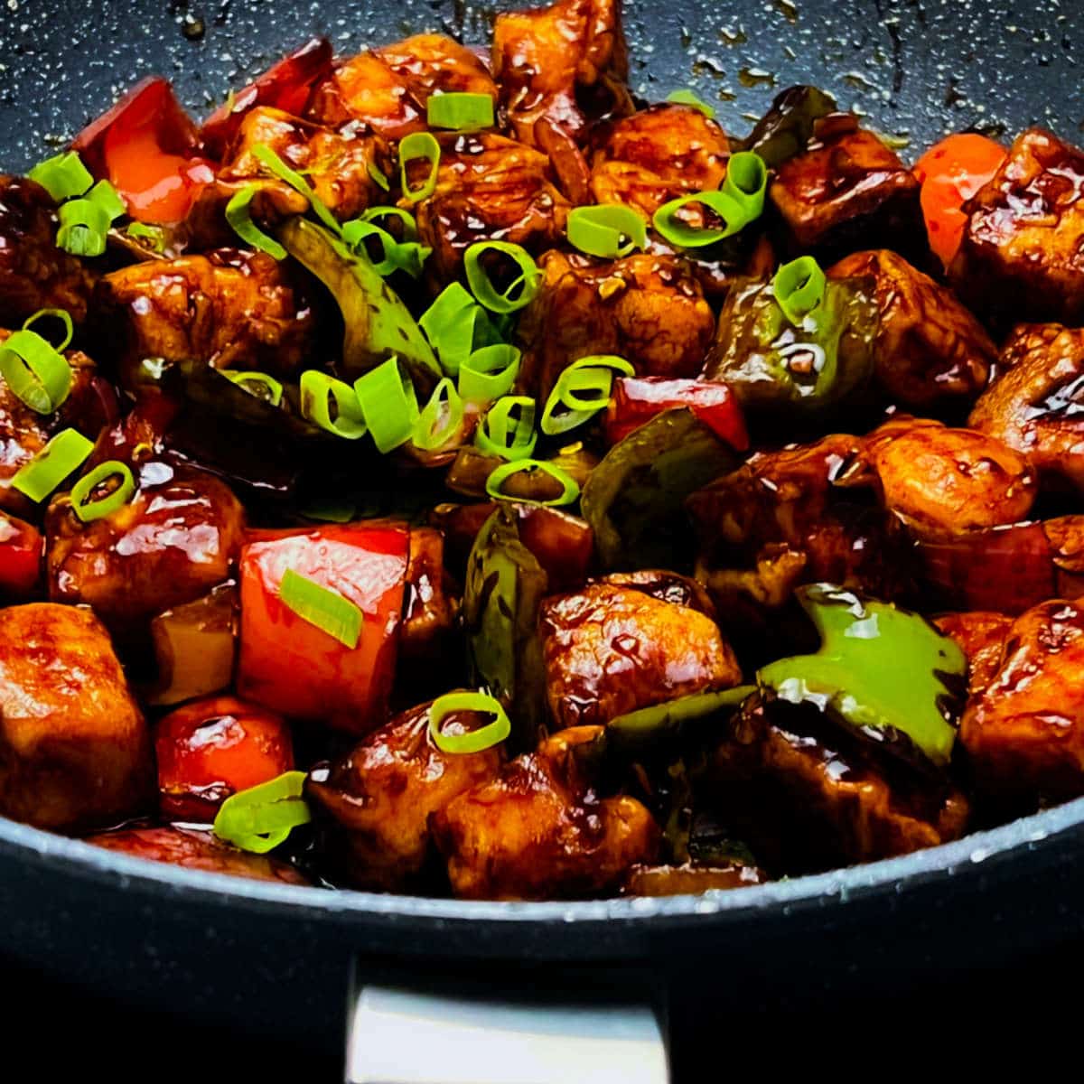 Step showing the mixing and tossing of chilli paneer in a frying pan.