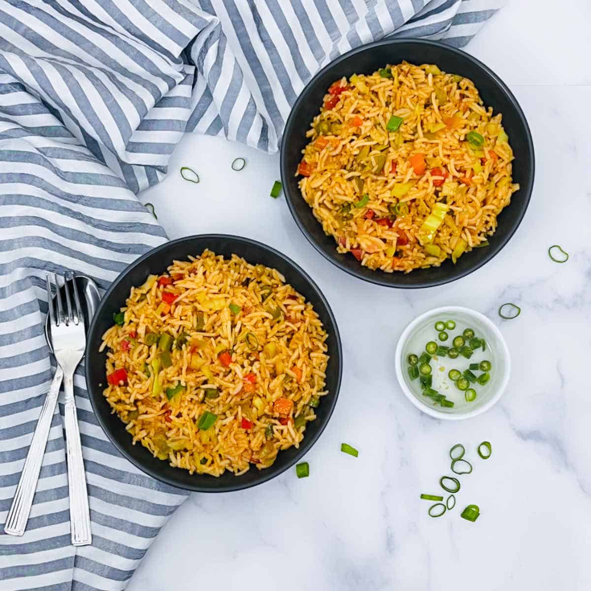 Bowls of vegetable fried rice on a marble surface.