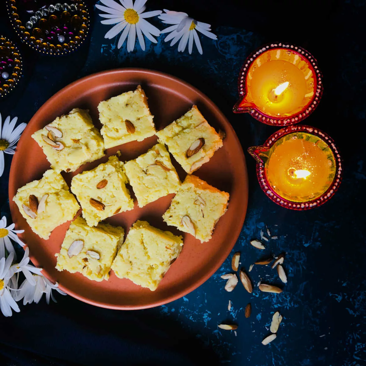 Milk barfi placed on a plate along with Diwali lights.