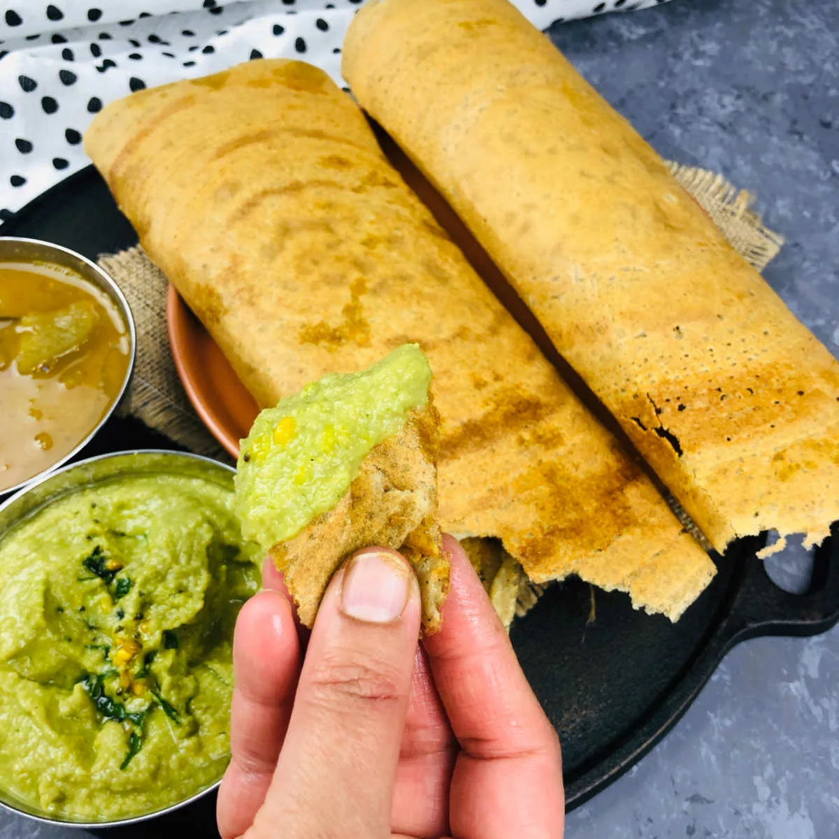 Piece of millet dosa dipped in chutney.