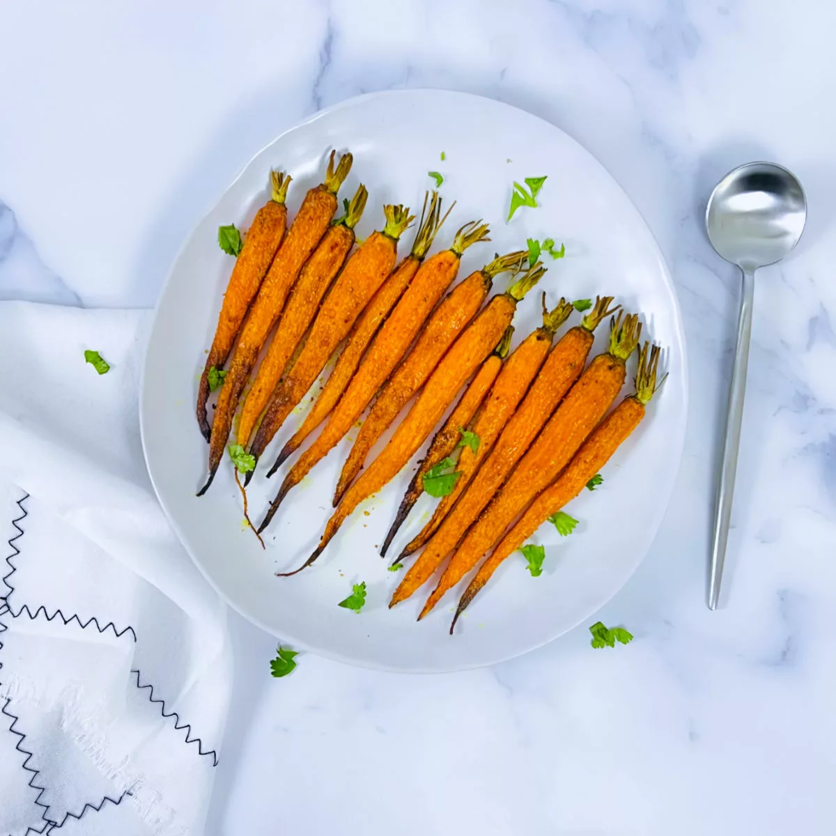 Curried roasted carrots placed on a white plate.