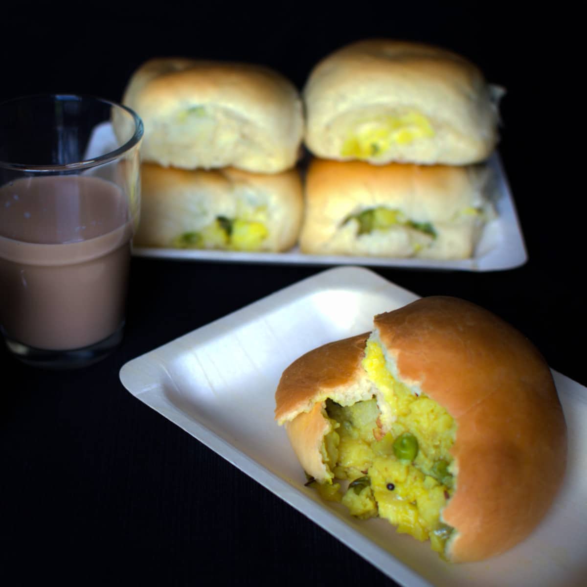 Palya buns served with masala chai on a black surface.