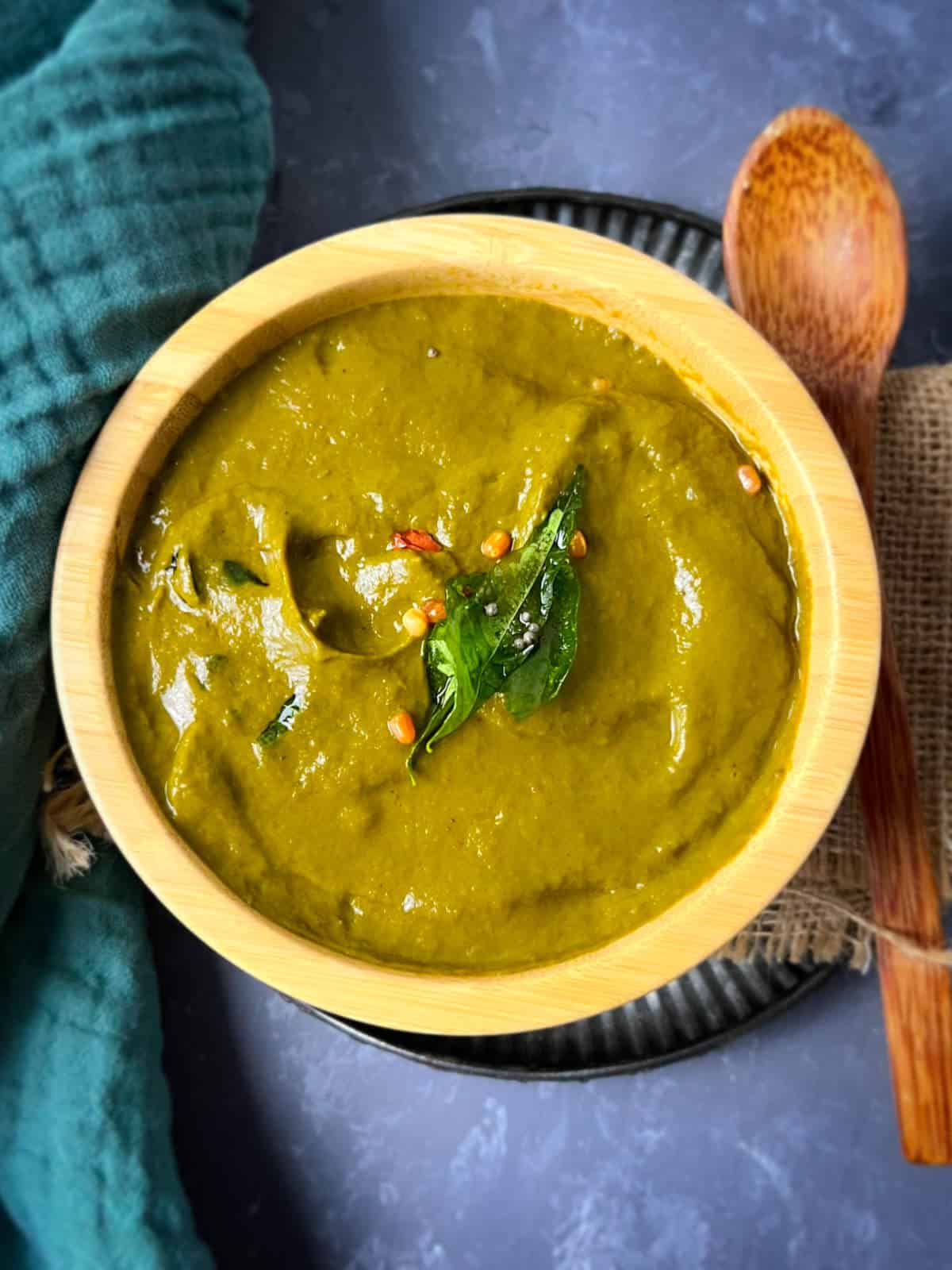 Malabar spinach chutney served in a wooden bowl with a wooden spoon.