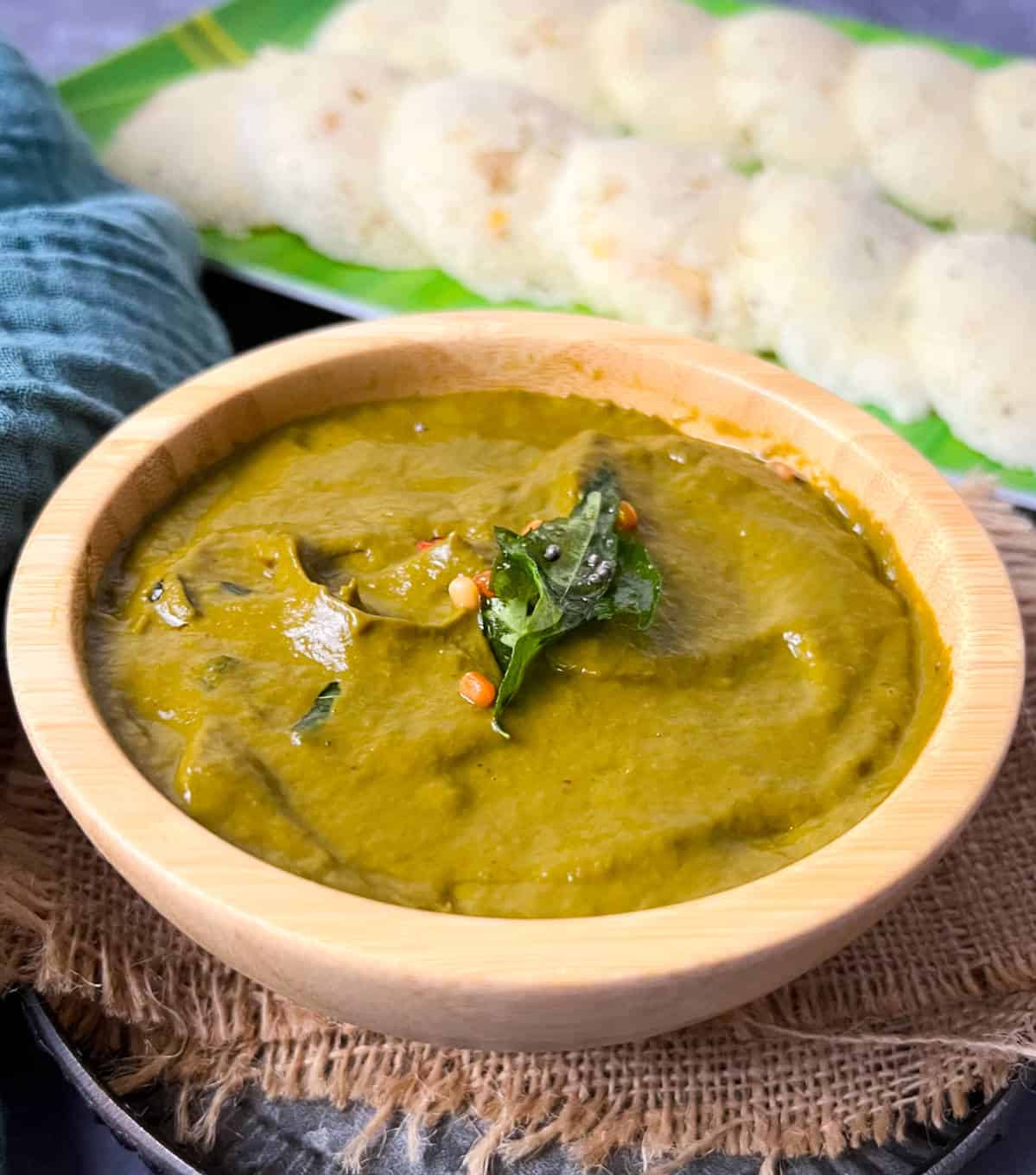 Malabar spinach chutney served in a bowl with rava idli in the background.