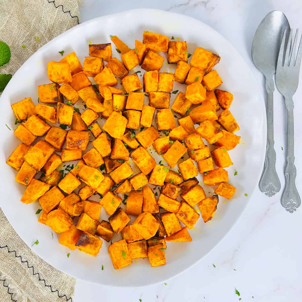 Air fryer roasted sweet potato cubes on a white plate.