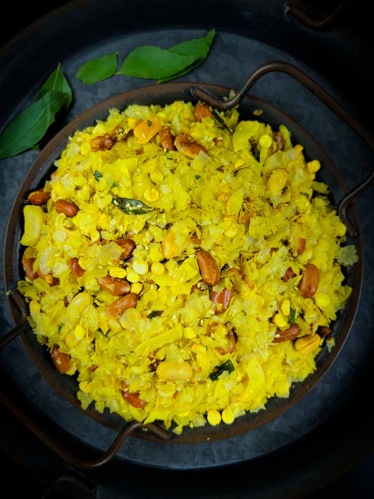 Poha chivda placed on a rusting black plate.