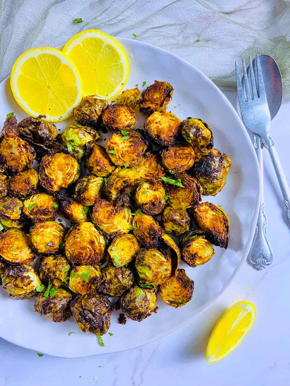 Air fryer brussels sprouts served with lemon on a white plate.