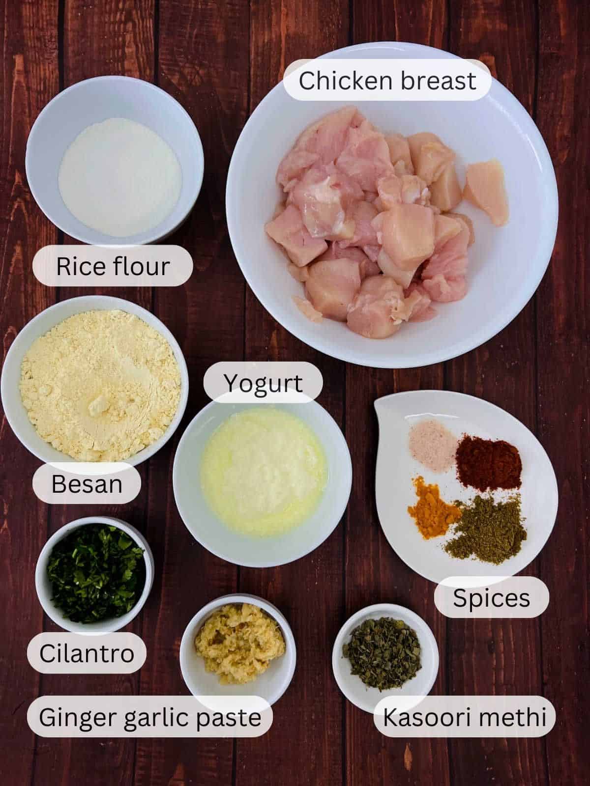 Ingredients required to make chicken pakora placed on a wooden board.