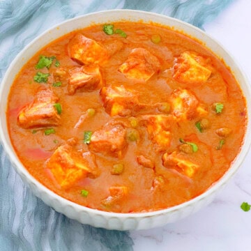 Matar paneer in a white bowl.
