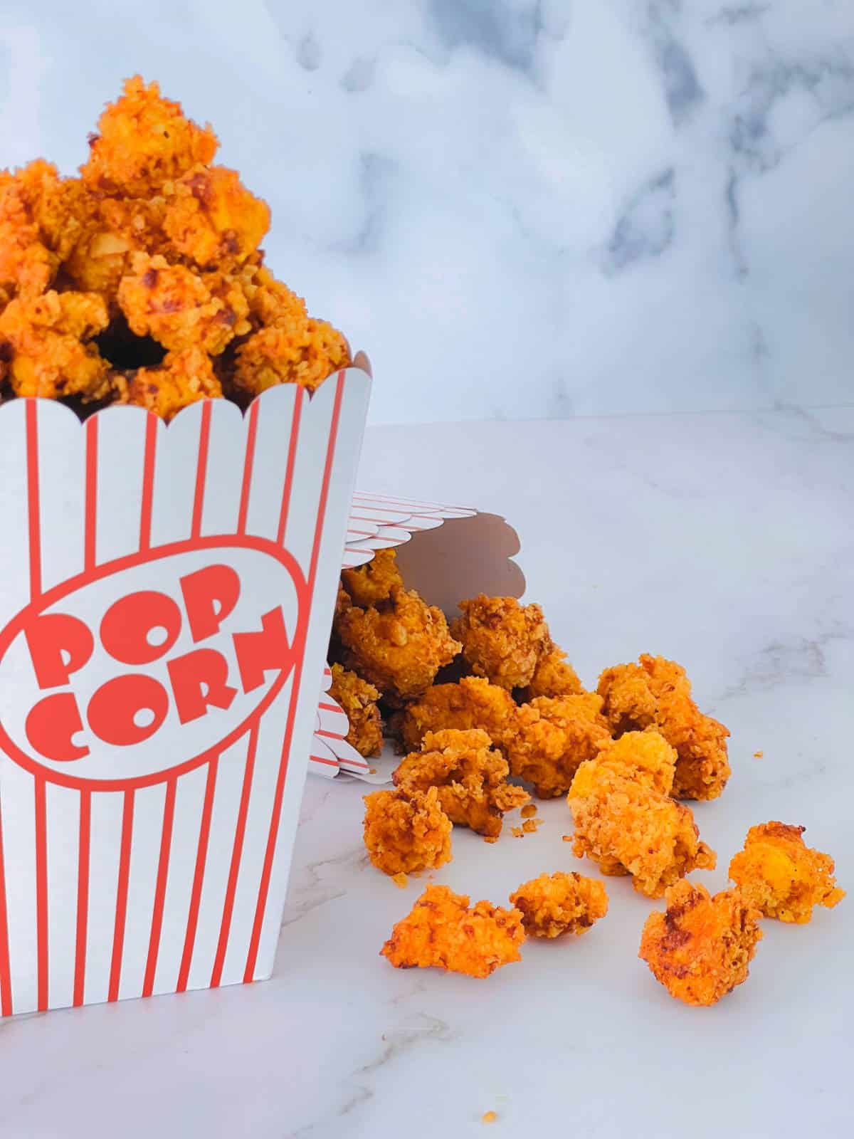 Popcorn chicken placed in paper box on a marble background.