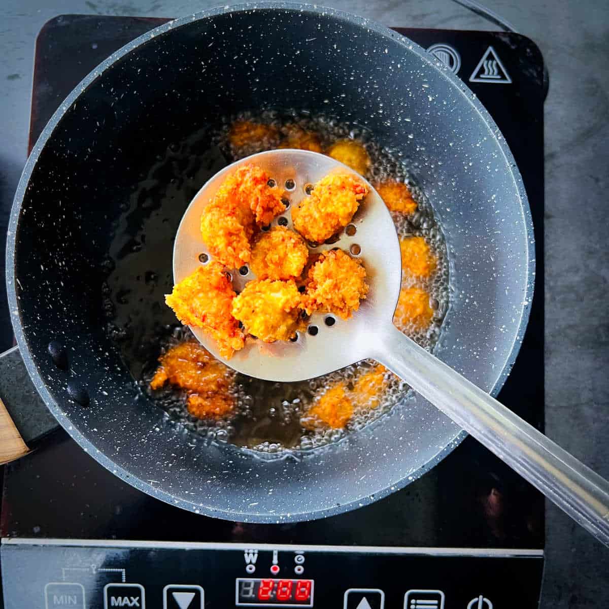 Popcorn chicken on a strainer after deep frying.
