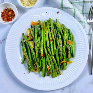 AIr fryer green beans placed on a white plate.