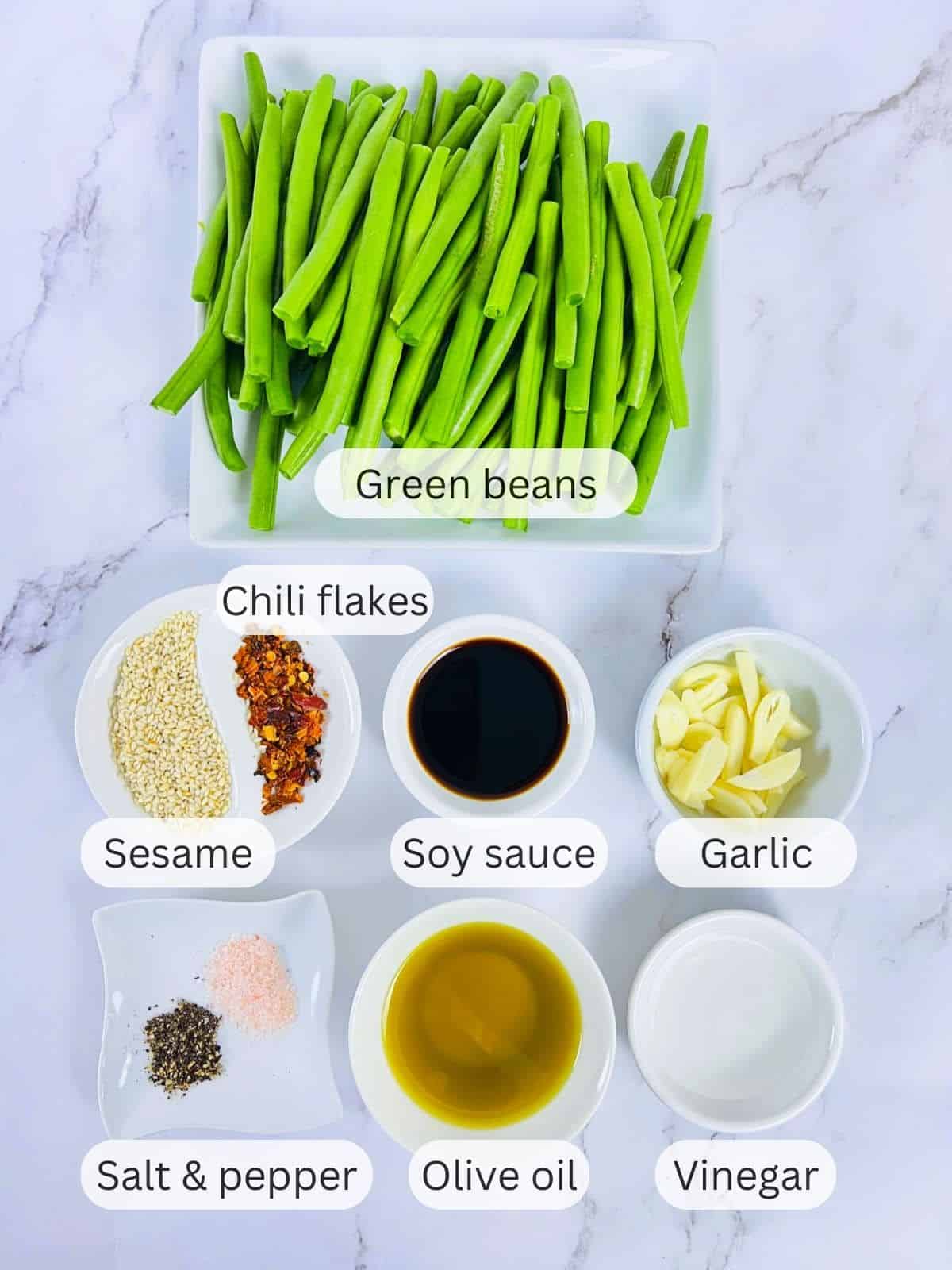 Ingredients to make air fryer green beans placed on a marbel background.