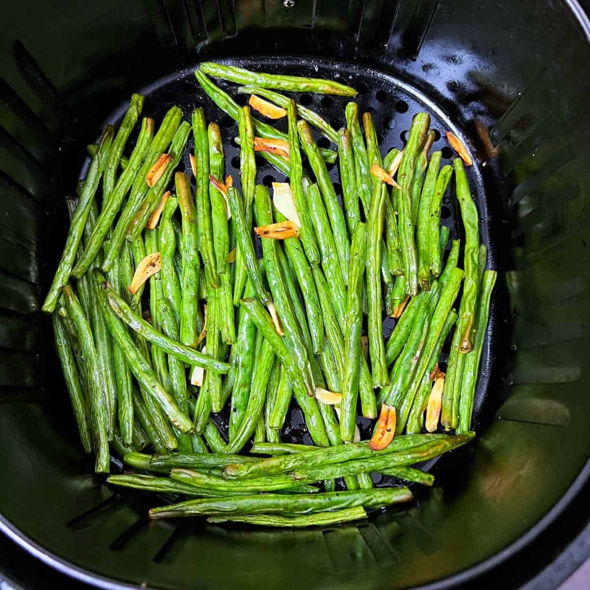 Air fried green beans placed in the air fryer basket.
