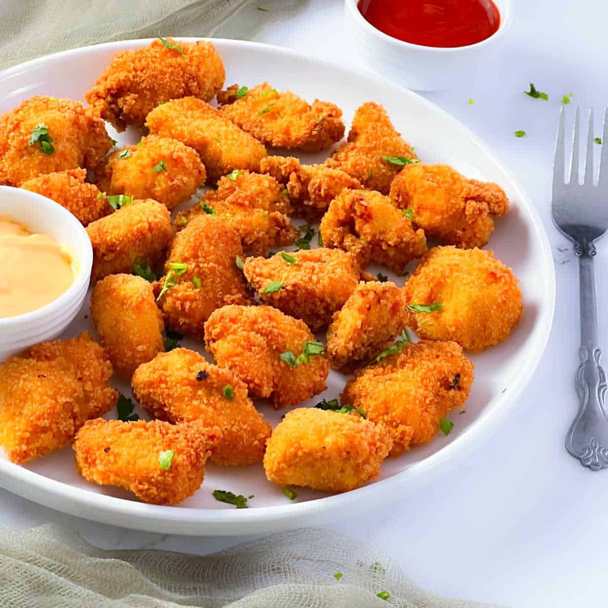 Chicken nuggets placed on a white plate.