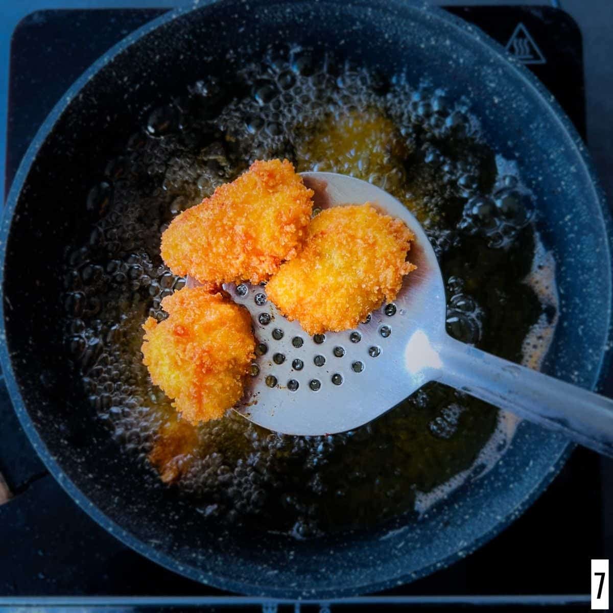 Deep fried chicken nuggets on a strainer.