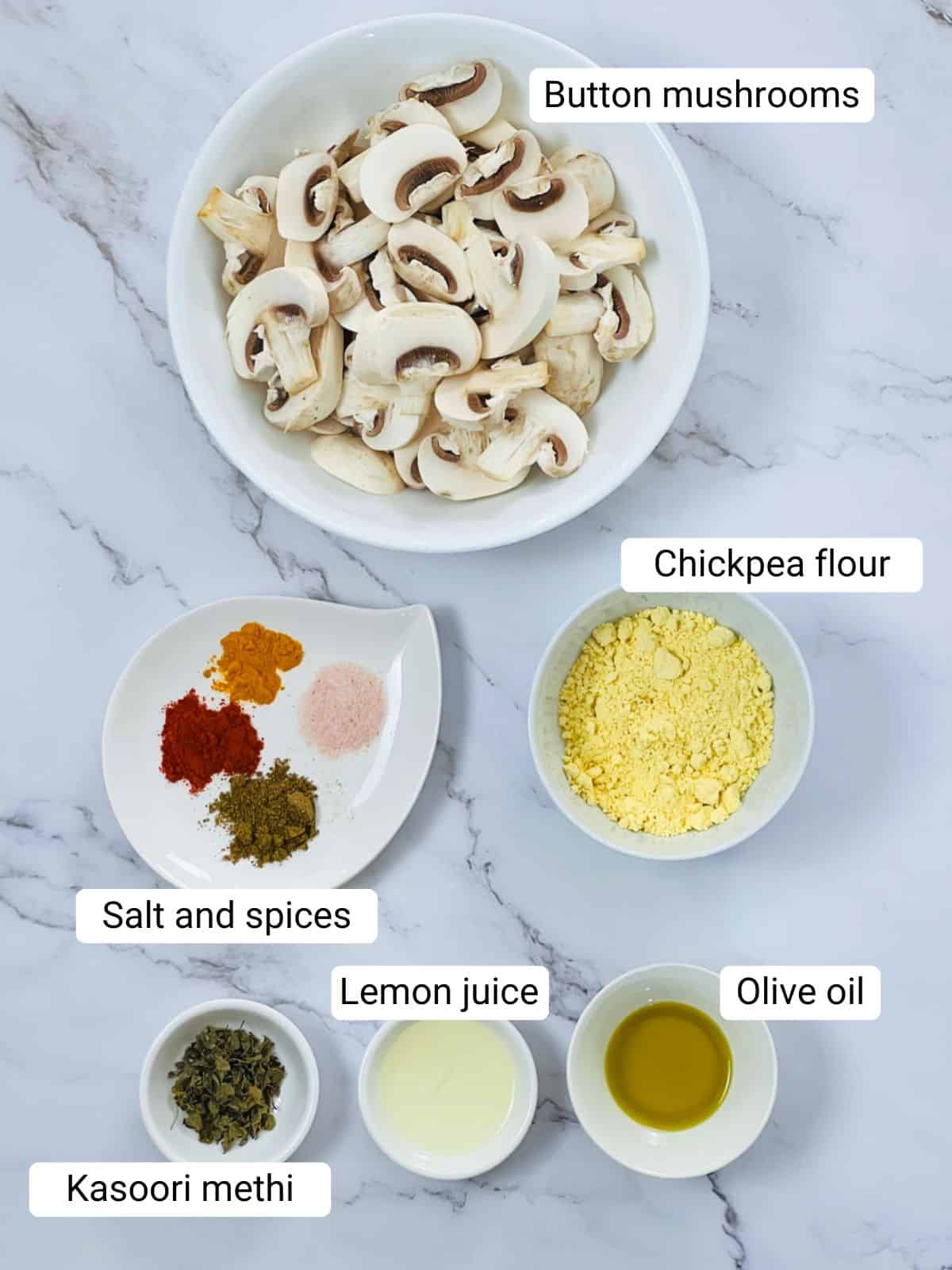 Ingredients to make air fryer tandoori mushroom placed on a marble surface.