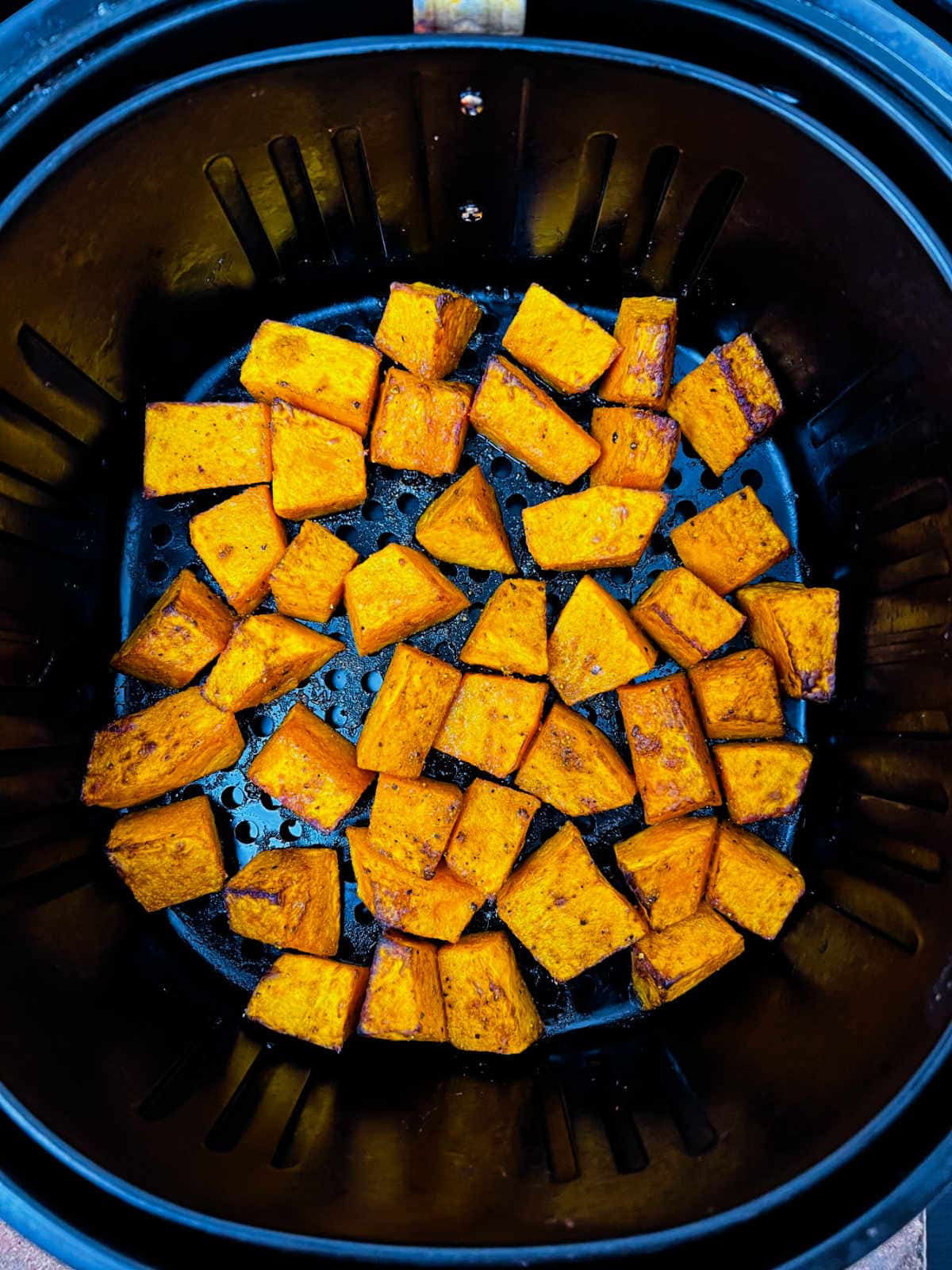 Crispy air fried pumpkin cubes in the air fryer basket.