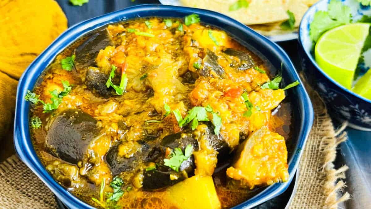 Aloo baingan or Indian potato eggplant curry served in a blue bowl.