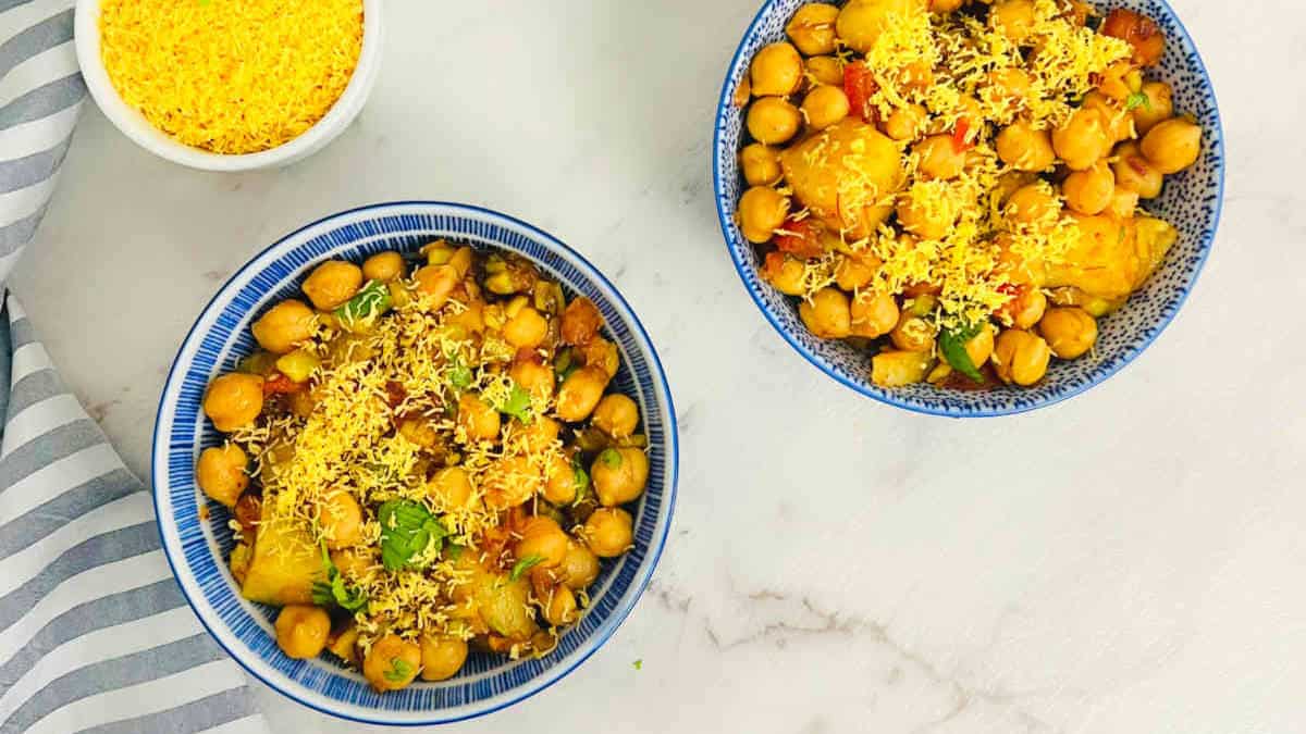 Two bowls of chana chaat on marble surface.