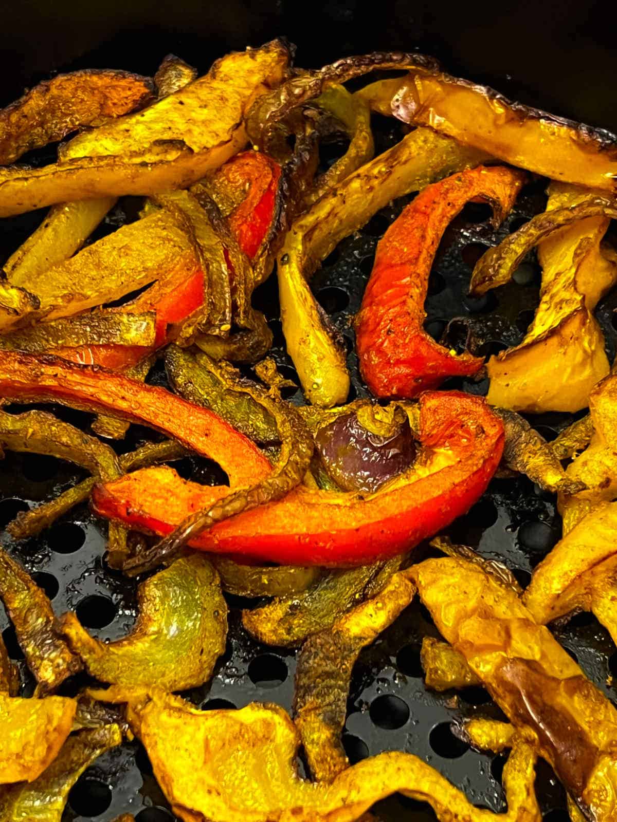 Close up of curry roasted bell peppers in air fryer basket.