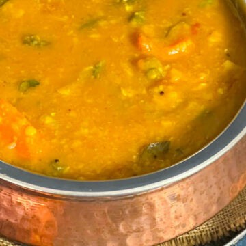 Vegetable sambar served in a traditional copper vessel.