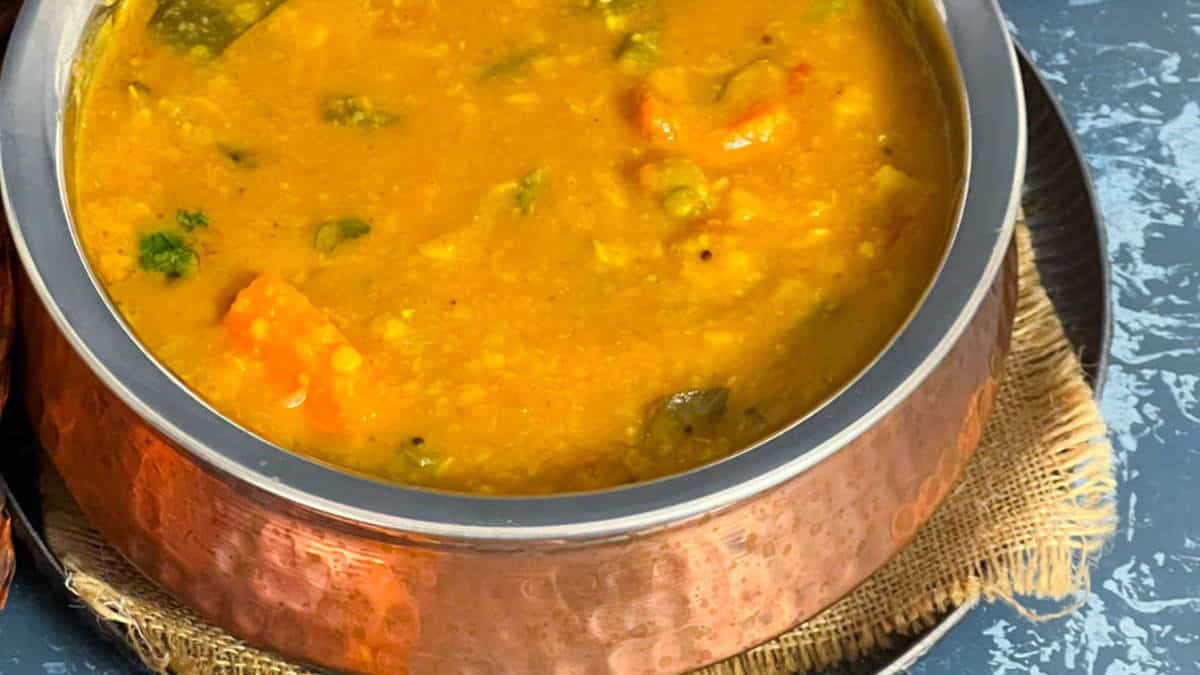 Vegetable sambar served in a traditional copper vessel.