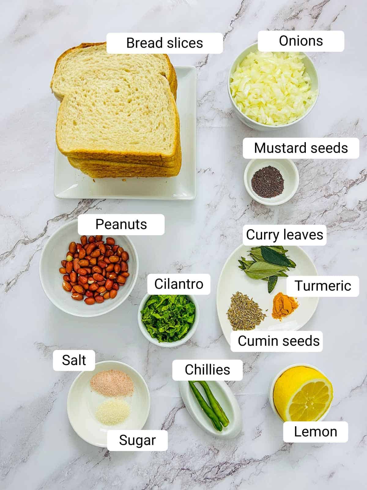 Ingredients to make bread upma placed on a marble surface.