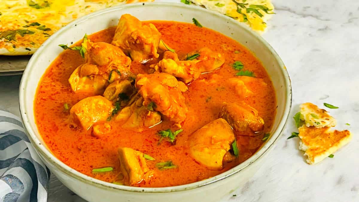 Butter chicken in a bowl served with naan.