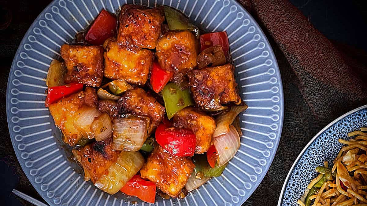 Chilli paneer on a grey plate.