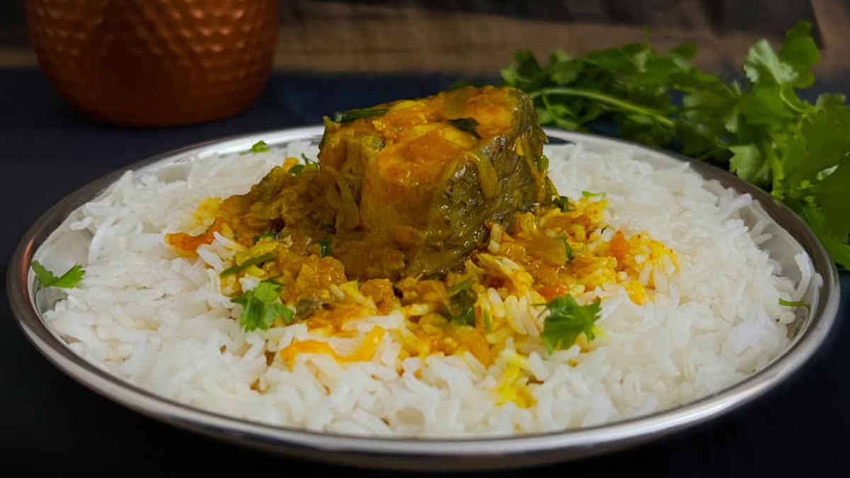Fish curry served on a bed of rice in a steel plate.