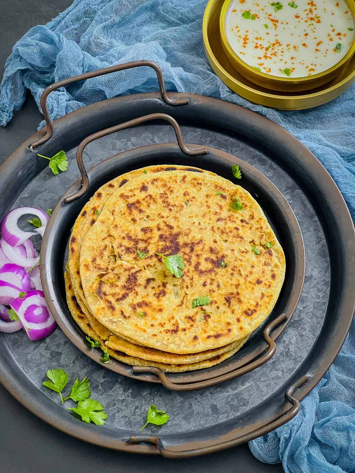 A stack of gobi paratha placed on a black plate.