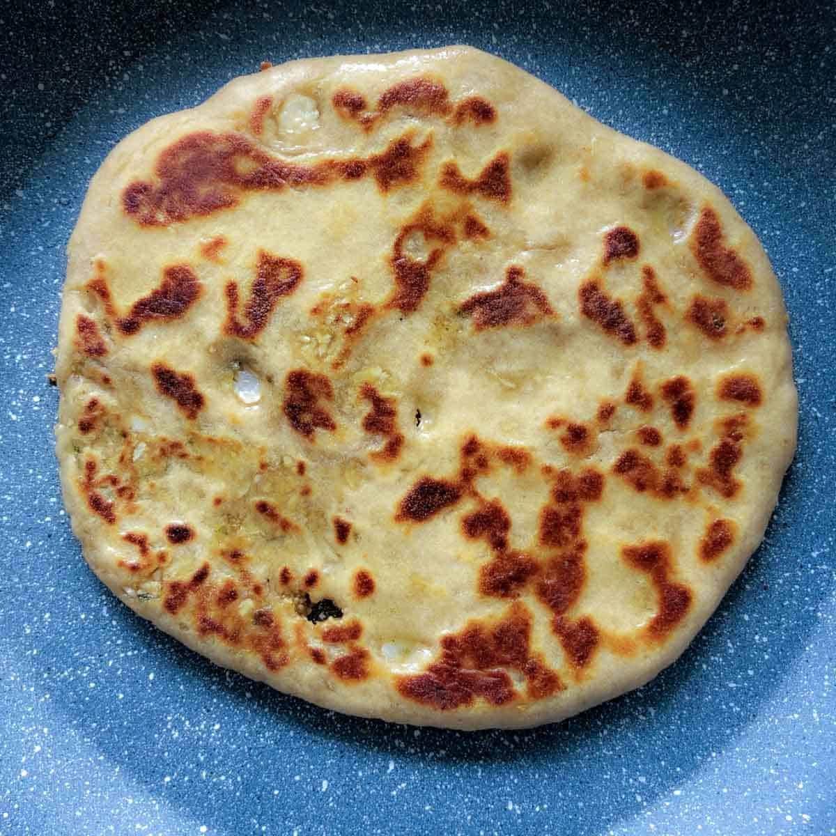 Step showing the cooking of second side of the paratha on the griddled.