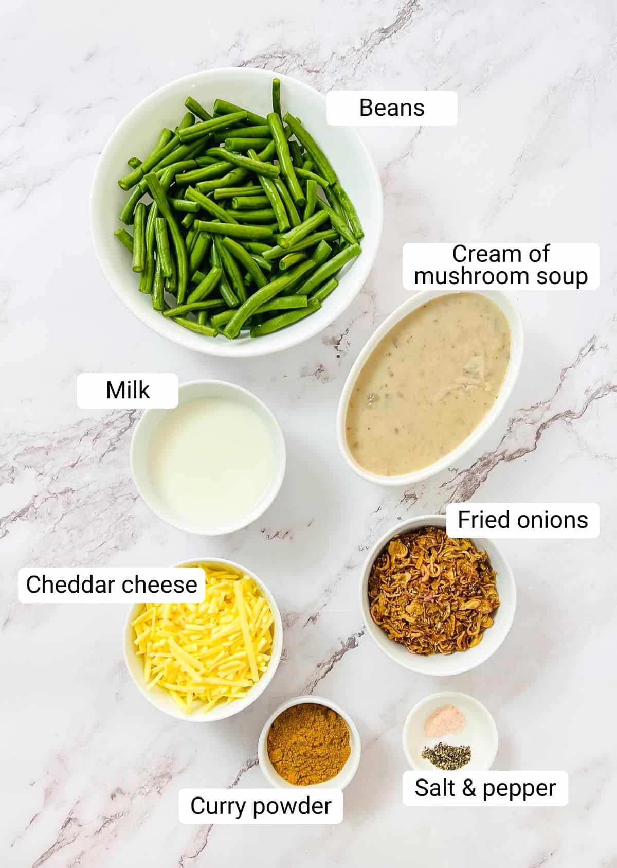 Ingredients to make green bean casserole placed on a marble surface.