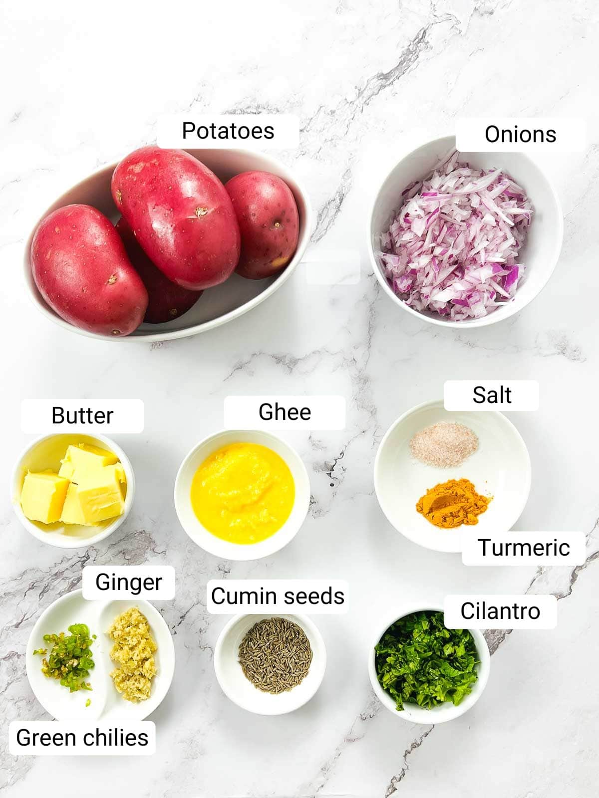 Ingredients to make masala mashed potatoes placed on a marble surface.