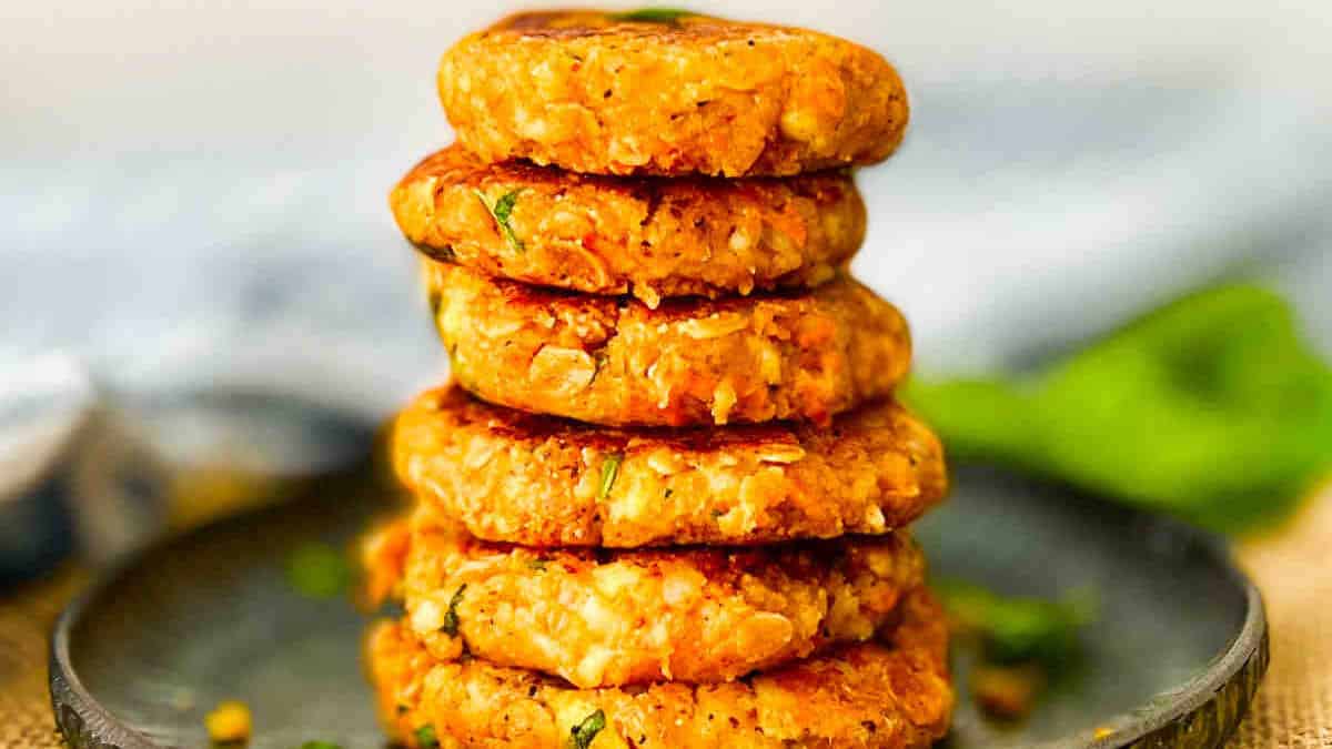 A stack of potato paneer cutlet on a black plate.