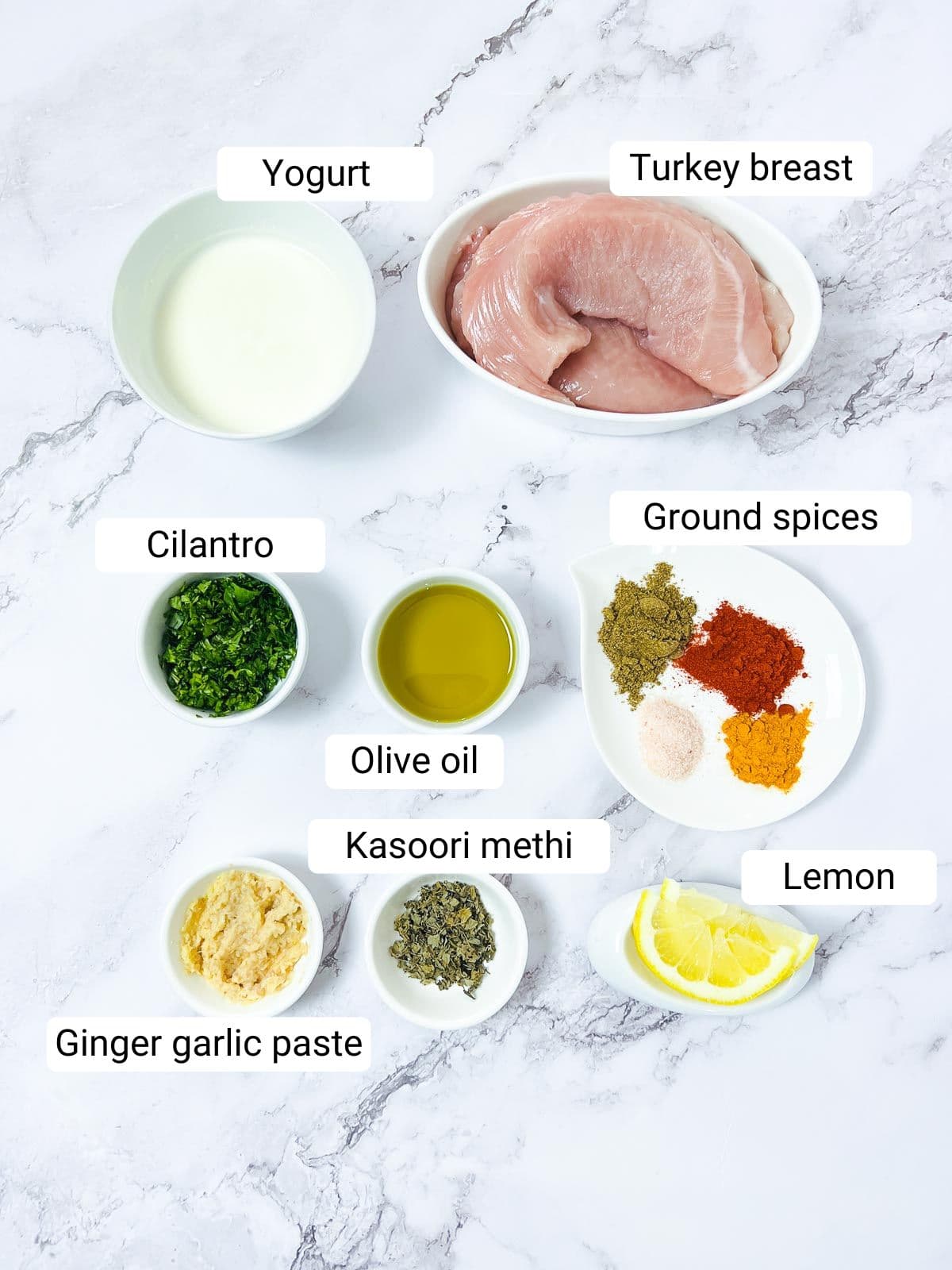 Ingredients to make tandoori turkey placed on a marble surface.