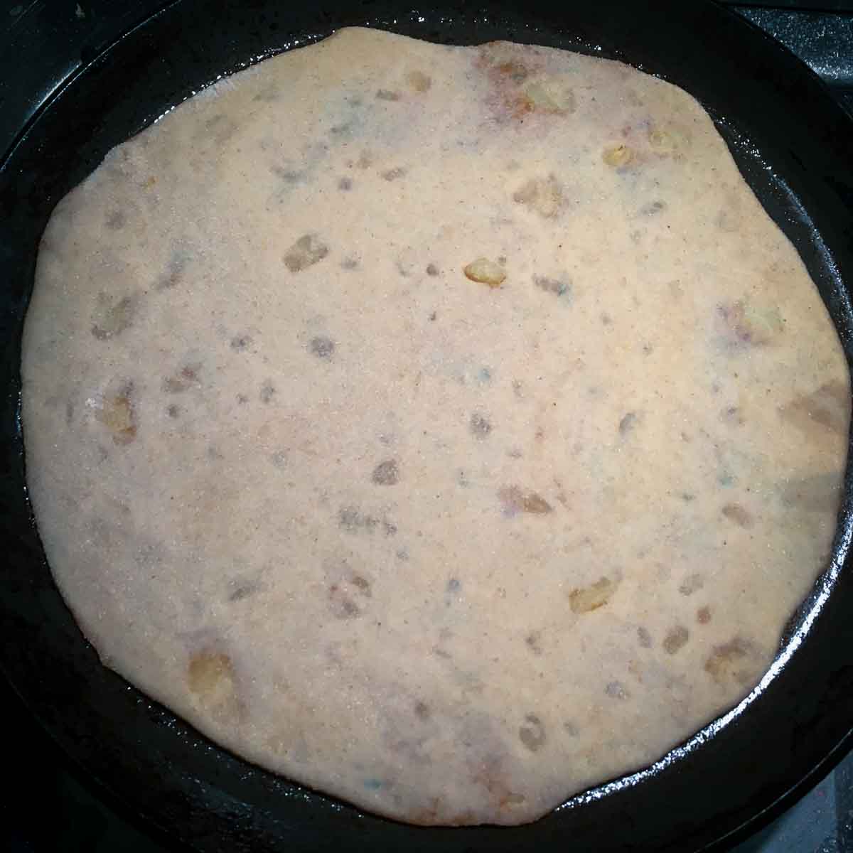 Step showing the rolled aloo paratha cooking on a hot tawa.