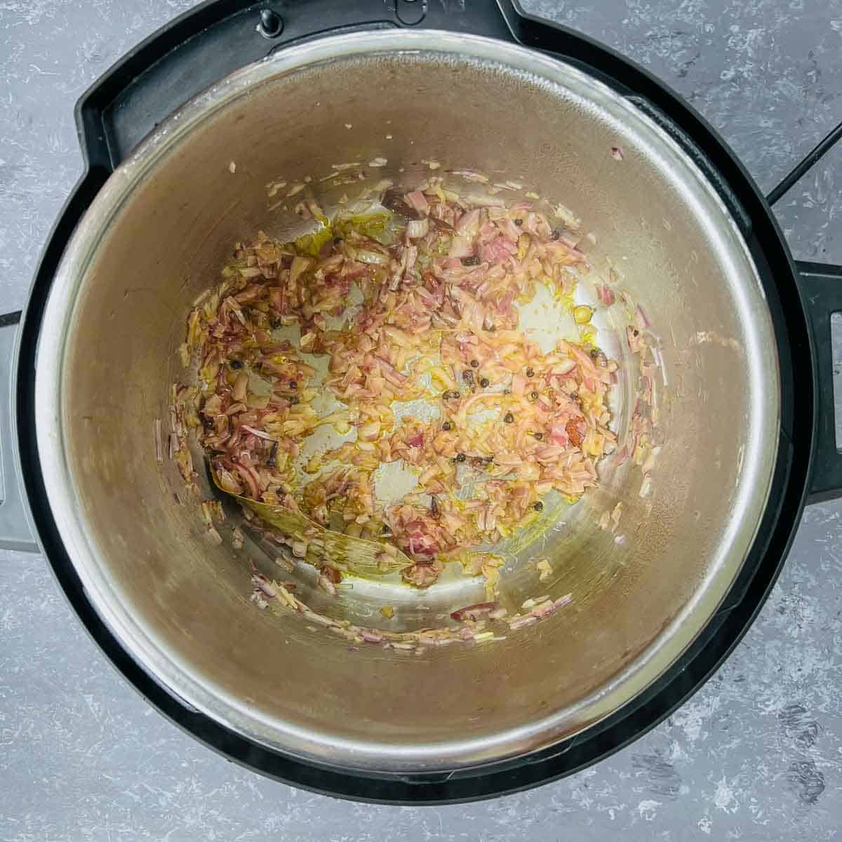 Saute whole spices and onions in the Instant Pot.